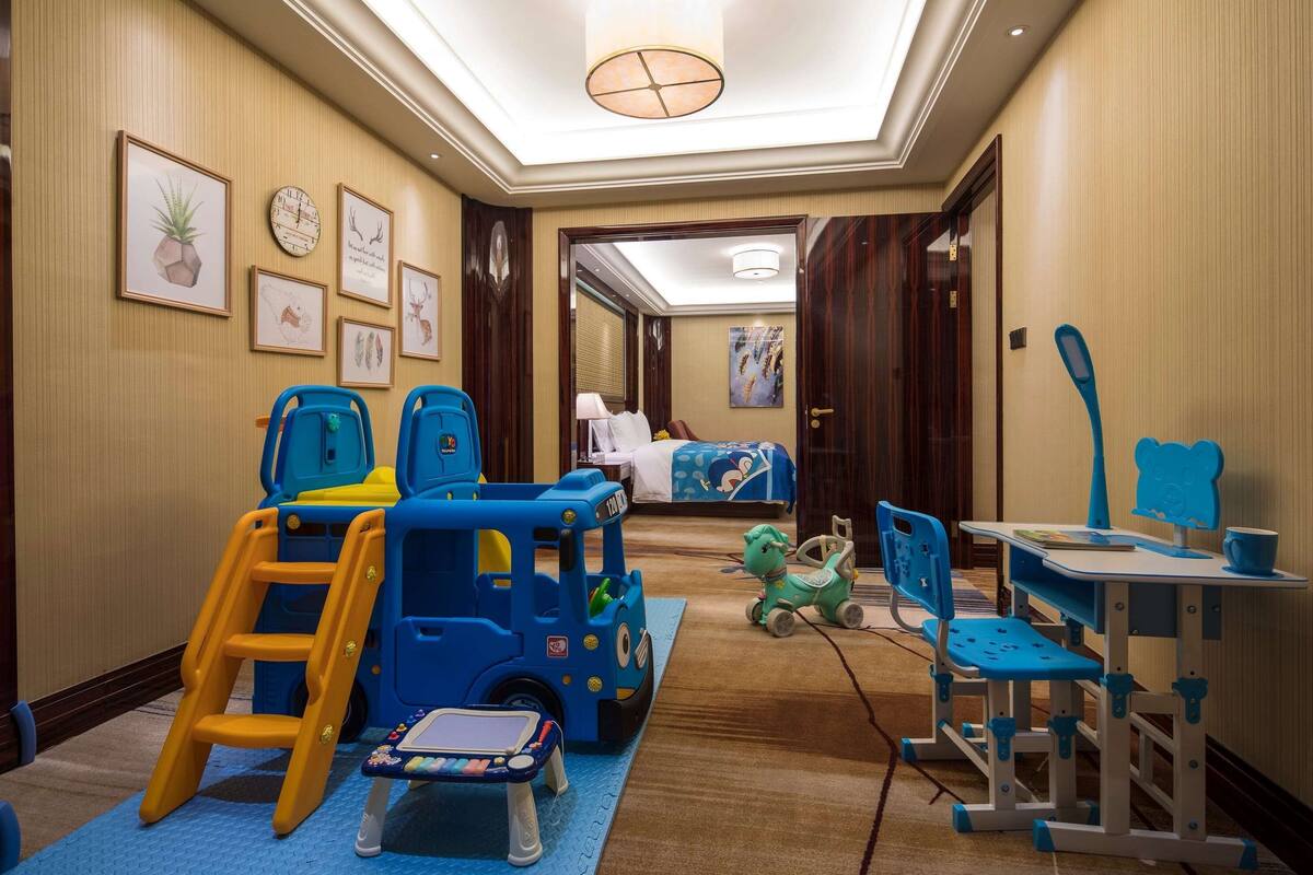 A children's play area with a blue toy truck, a green toy car, and a play table.