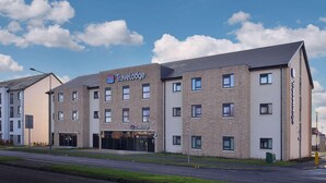A Travelodge hotel with a modern brick facade, multiple windows, and a flat roof. - Travelodge Plus Edinburgh Park (Edinburgh)