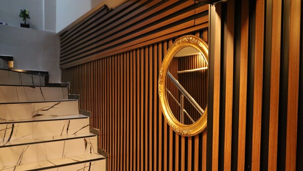 A staircase with marble steps and a wooden panel wall with a gold-framed mirror. - Galaxy Hotel Sultanahmet (Istanbul)
