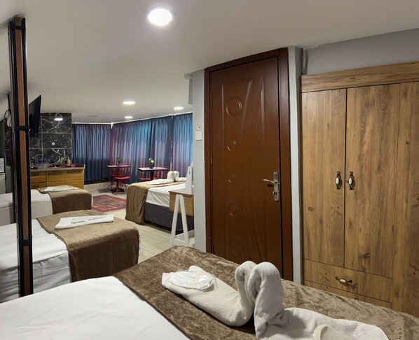 A hotel room with a bed, a desk, a wardrobe, and a dining area with a table and chairs.
