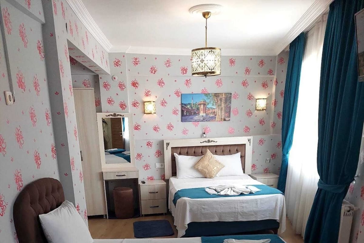 A hotel room with two beds, a sitting area, a mirror, and a chandelier.
