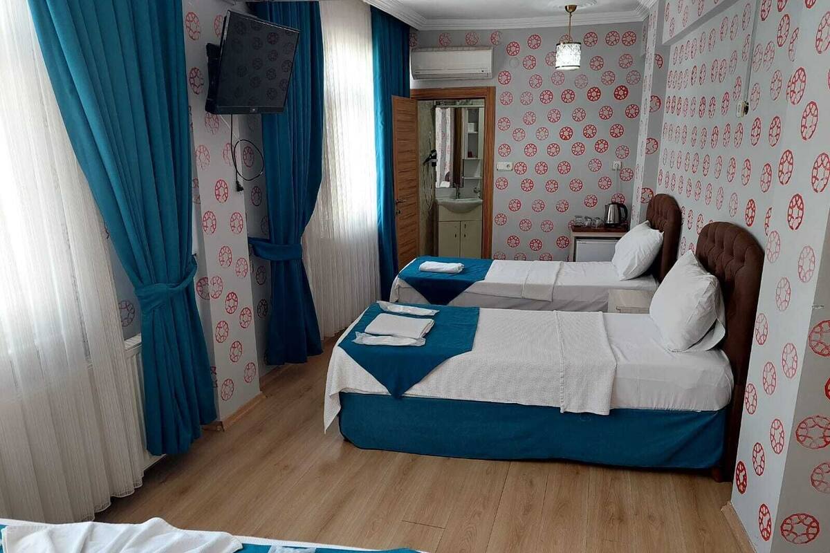 A hotel room with two beds, a TV, a sink, and a mirror.