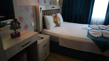 A hotel room with a bed, bedside table, and a small desk.