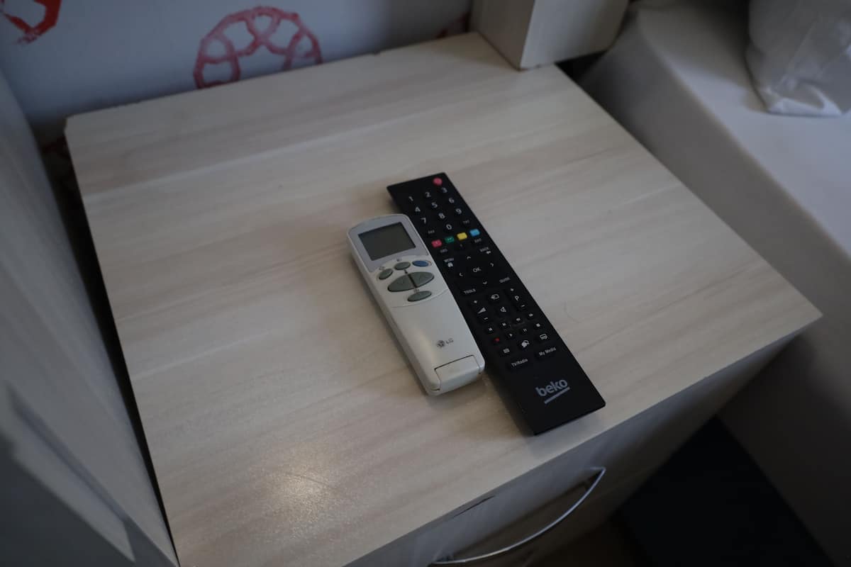 A remote control and a black device on a wooden table.