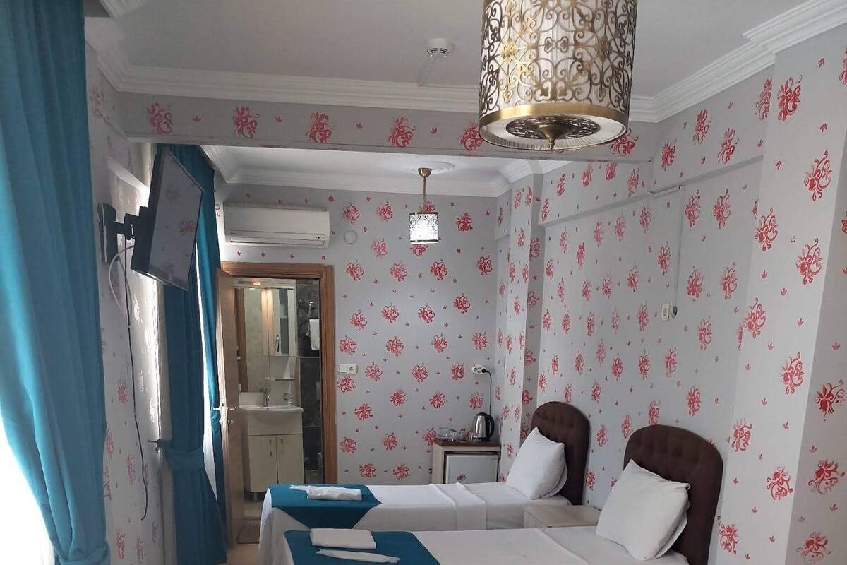 A hotel room with two beds, a bathroom, and a kitchenette.