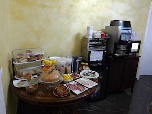 A breakfast buffet with various food items, a coffee machine, and a microwave. - Roma Royal Residence (Rome)