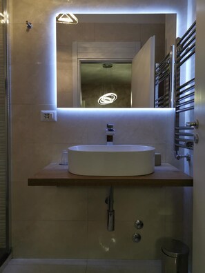 A modern bathroom with a large mirror, a round sink, and a towel rack. - Roma Royal Residence (Rome)