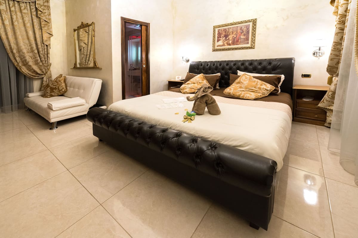 A spacious bedroom with a large bed, a sofa, and a nightstand.