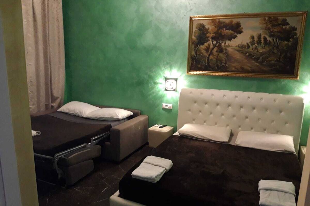 A room with a bed, a small table, and a painting on the wall.