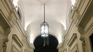 A grand hallway with ornate columns, a central chandelier, and a recessed ceiling. - Roma Royal Residence (Rome)