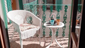 A wicker chair and a small table with a teapot and cup on a tiled patio. - Cozy apartment near Chatedral and Medici Chapels (Firenze)