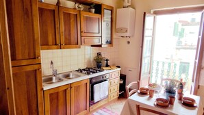 A kitchen with wooden cabinets, a gas stove, a sink, and a dining area with a table and chairs. - Cozy apartment near Chatedral and Medici Chapels (Firenze)