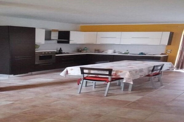 A compact kitchen with dark cabinets, a white countertop, and a dining table with two chairs.