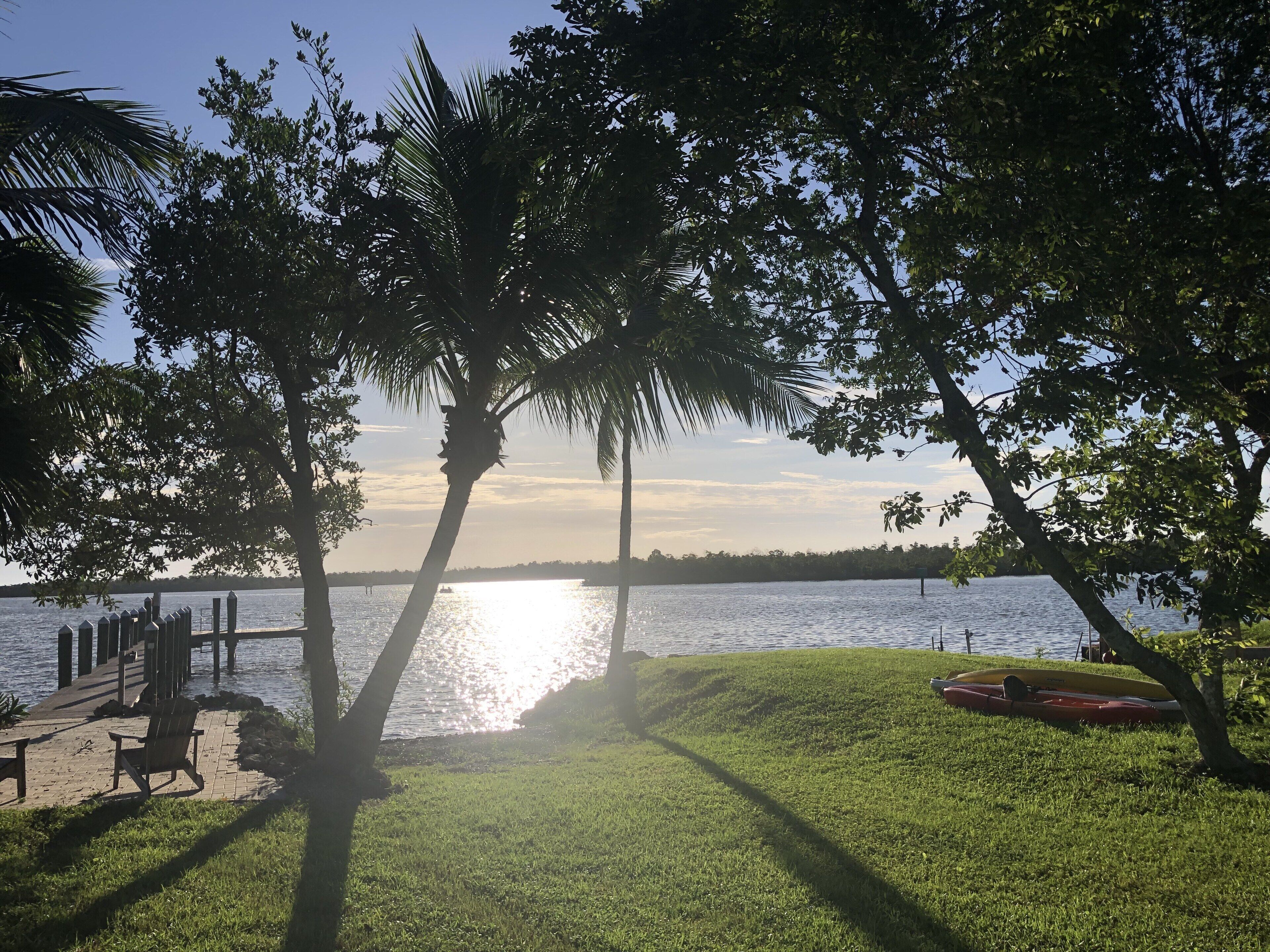 A lakeside view with a dock, a grassy area, and a boat.
