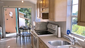 Una cocina con armarios de madera, un lavamanos de acero inoxidable y una zona de comedor con mesa y sillas.