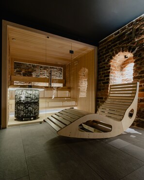 A modern sauna with wooden benches and a stone wall. - Hotel Spichrz (Torun)