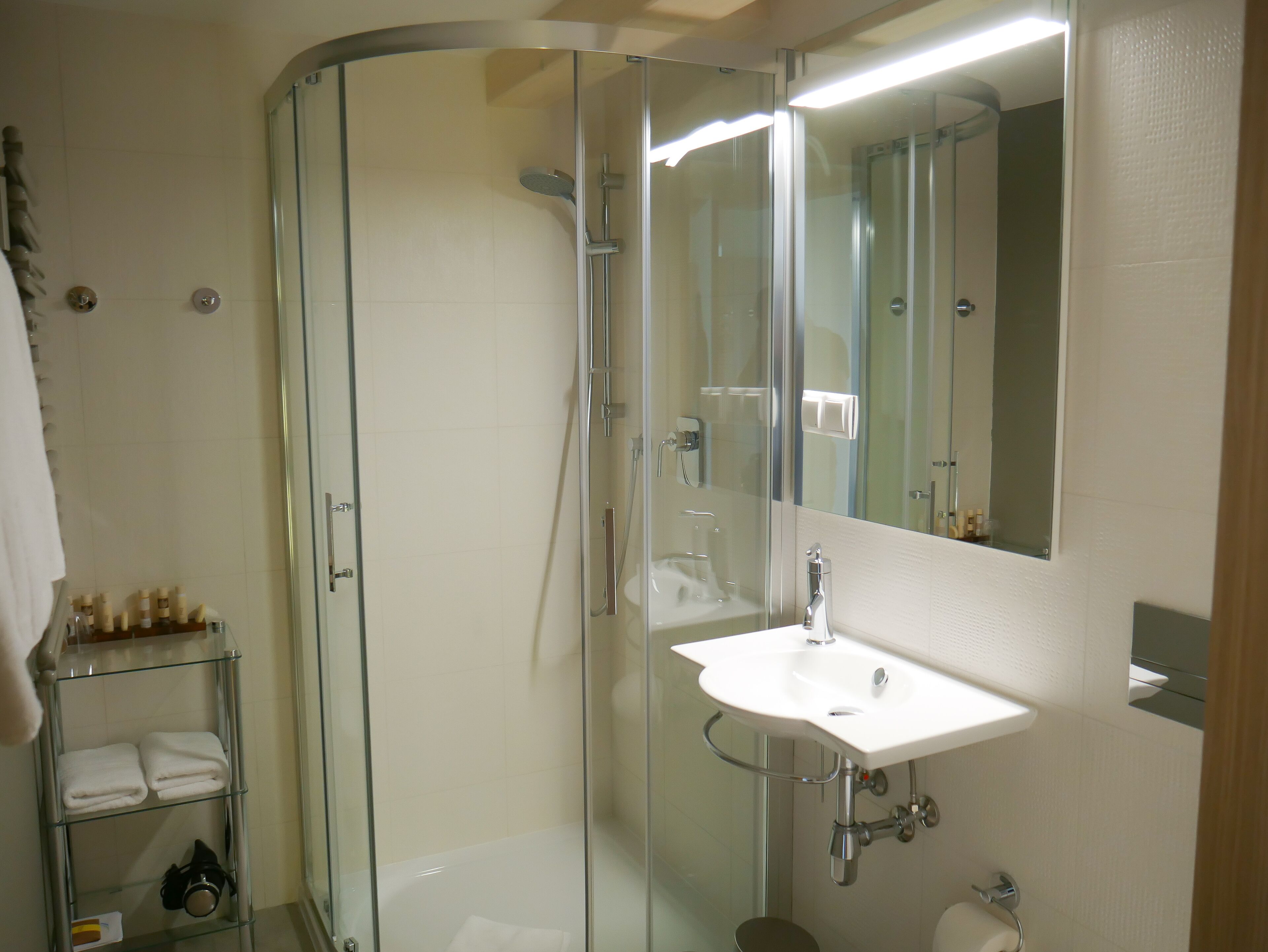 A modern bathroom with a glass-enclosed shower, a white sink, and a mirror.