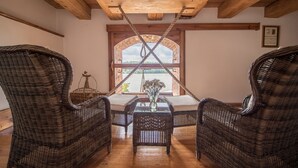 Una habitación con mobiliario de mimbre, techo de madera y ventana con vistas.