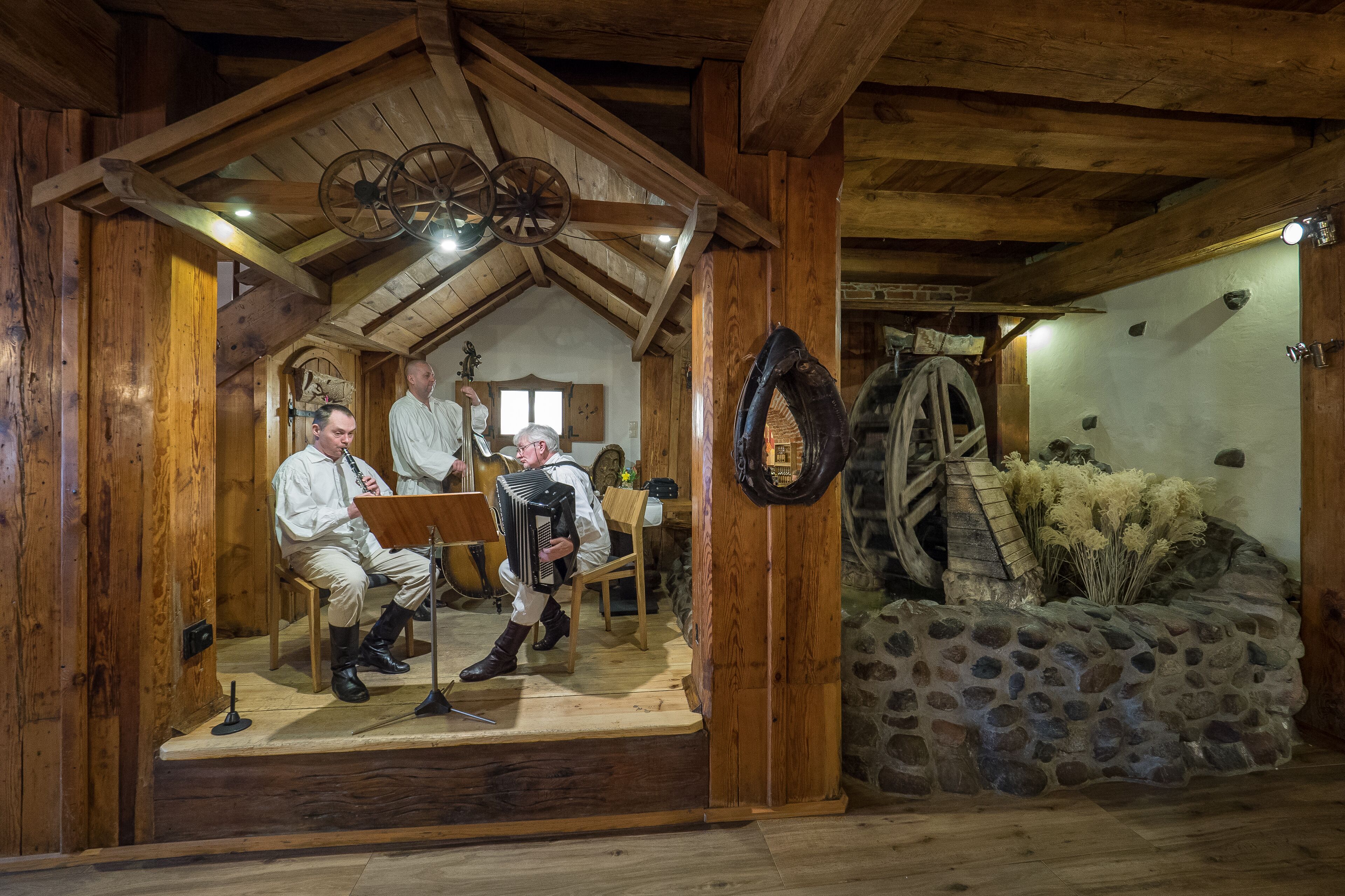 A rustic wooden interior with a stage, musical instruments, and a stone wall.