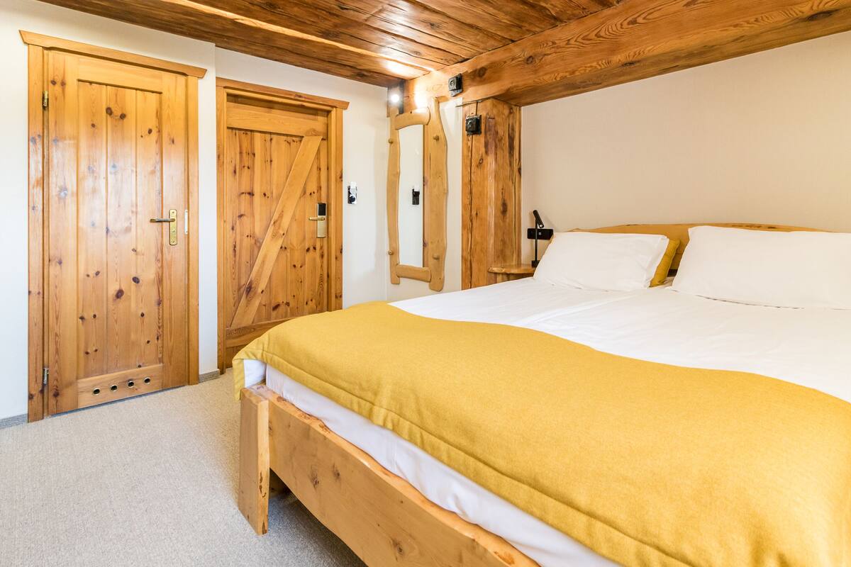 Un dormitorio de madera con una cama grande, un armario de madera y una puerta de madera.
