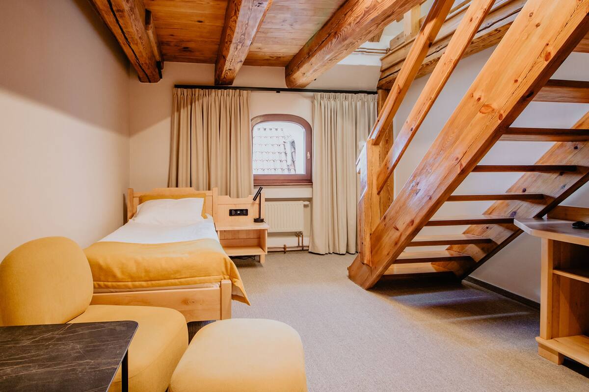Una habitación acogedora con cama, dos sillones, un escritorio y una ventana con cortinas.