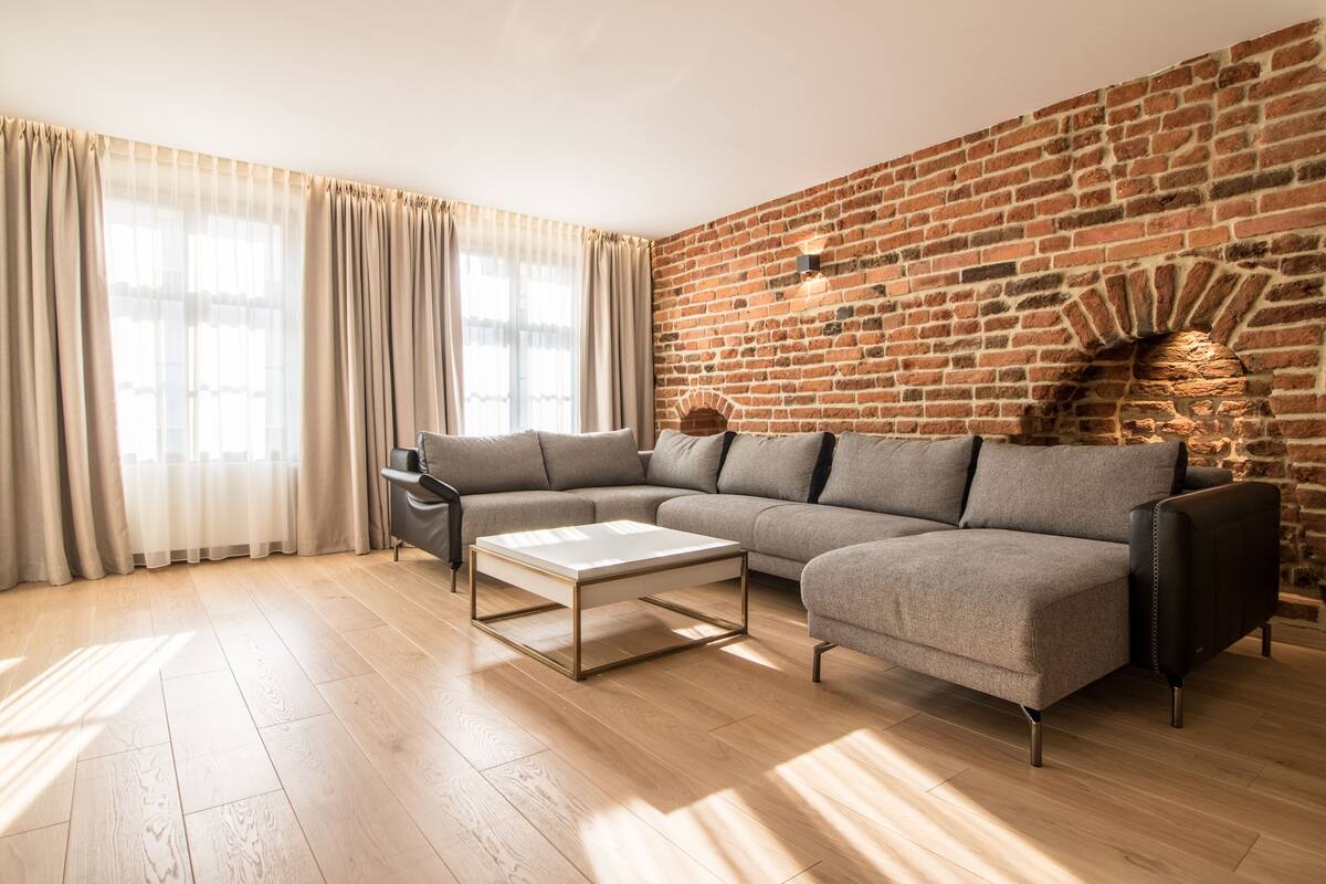 Una sala de estar moderna con un sofá modular, una mesa de centro de vidrio y una pared de ladrillo.