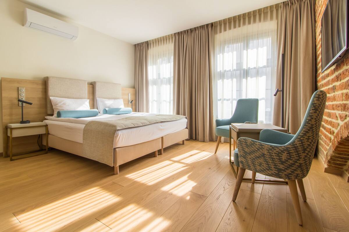 Una habitación de hotel con cama, mesitas de noche, una silla y televisor.