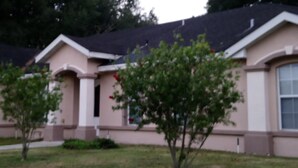 A residential house with a beige facade, a dark roof, and a small tree in the front yard. - CLEAN, COMFORTABLE, FULLY PRIVATE UNIT IN GATED COMMUNITY  (Ocala)