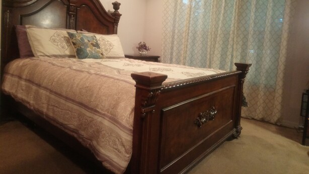 A bedroom with a wooden bed, a nightstand, and a window with sheer curtains. - CLEAN, COMFORTABLE, FULLY PRIVATE UNIT IN GATED COMMUNITY  (Ocala)