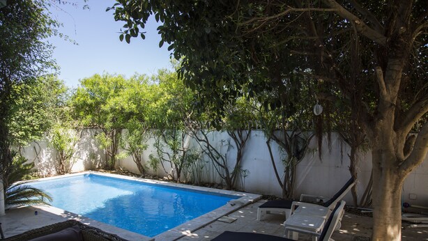 A swimming pool with lounge chairs and a wicker sofa. - Villa Malaga (Carthage)