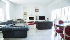 A modern living room with a sectional sofa, a red chair, a glass coffee table, and a flat-screen TV. - Villa Malaga (Carthage)