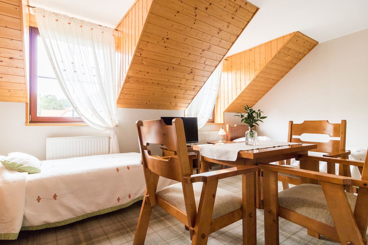 Una habitación acogedora con vigas de madera, una cama, un escritorio y una silla.