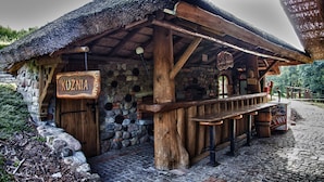 Un bâtiment rustique en bois, doté d’un mur en pierre et d’un toit de chaume.