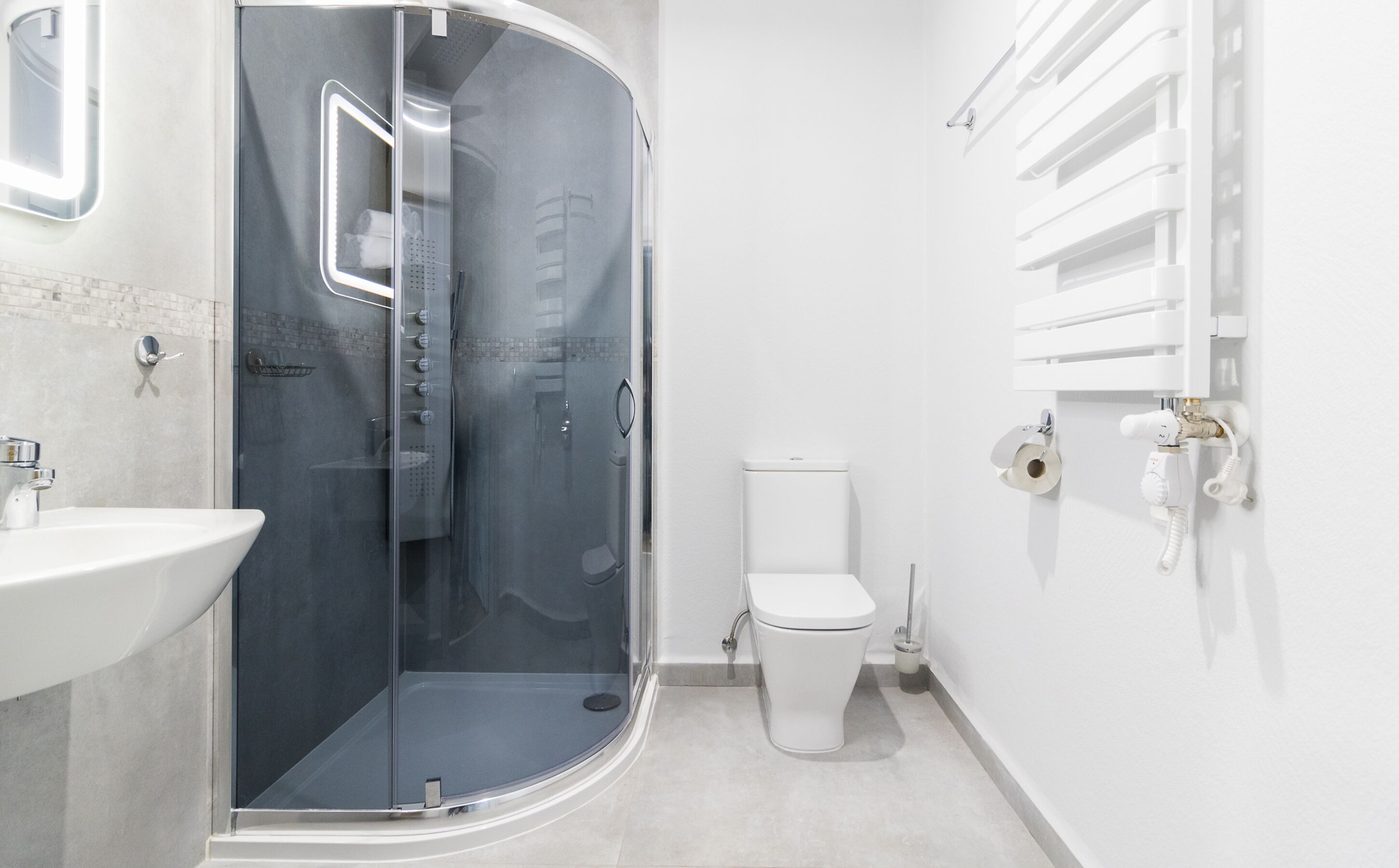 A modern bathroom with a glass-enclosed shower, a white toilet, and a sink.
