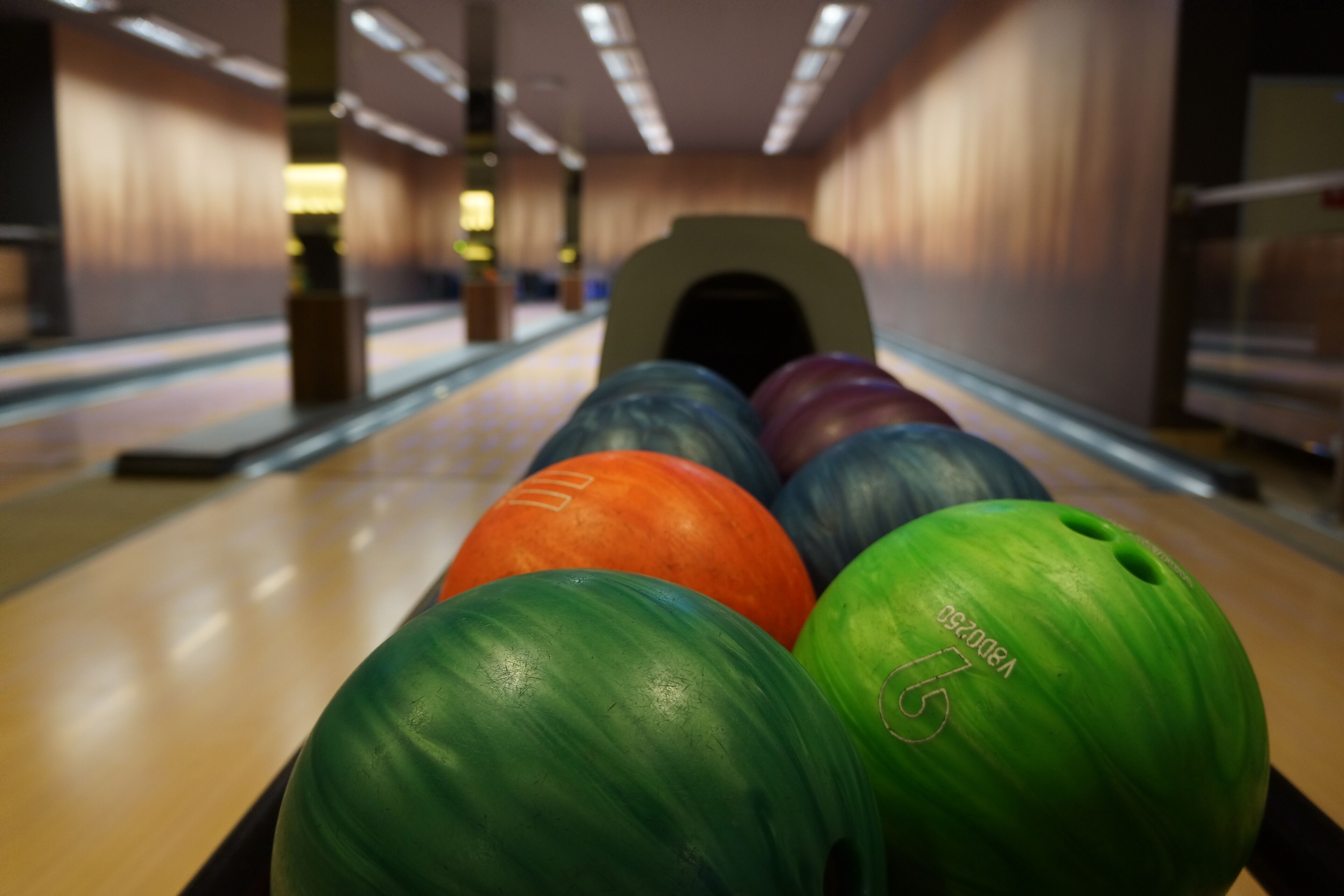 Eine Kegelbahn mit einer Spielfläche und Bowlingkugeln im Vordergrund.