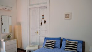 A bedroom with a bed, a bedside table, a dresser, a mirror, and a door with decorative items. - Hostel Via Zara (Palermo)