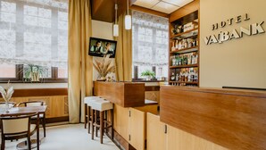 Un bar de hotel con mobiliario de madera, una pantalla de televisión y una nevera pequeña.