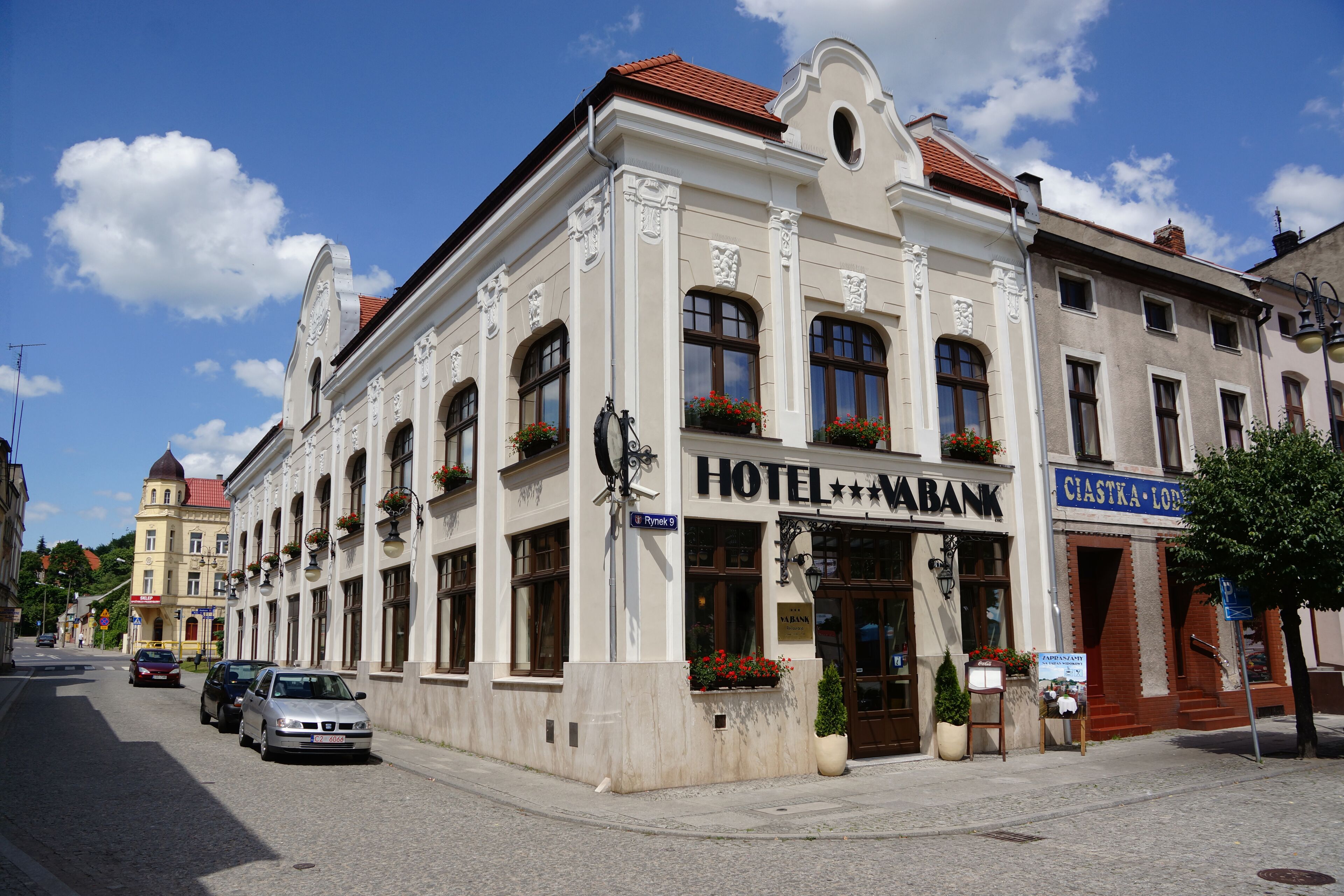 A historic building with a sign for 'HOTEL VABANK' and 'CIASTKA-LODZ'. It features classic architecture with arched windows and decorative moldings.
