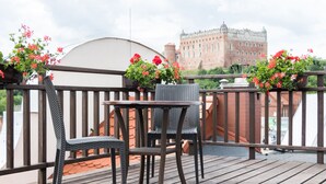 Un balcón con sillas de mimbre y una mesa, con vistas a un edificio histórico.