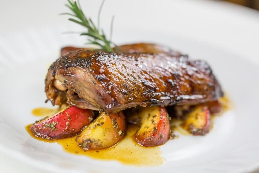 A dish with roasted meat and vegetables on a white plate.