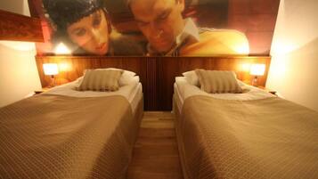 A hotel room with two single beds, wooden headboard, and a large poster above the beds.