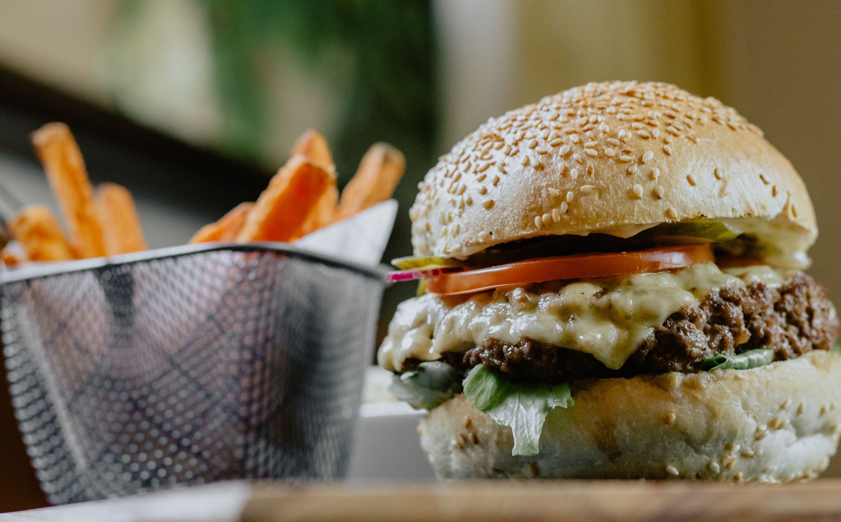 Un hamburger garni de fromage, de laitue, de tomate et servi dans un pain aux graines de sésame, accompagné d’une portion de frites.