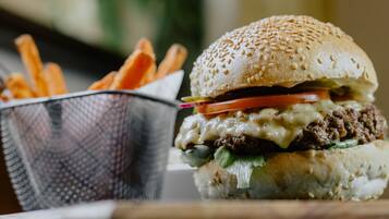 Un hamburger garni de fromage, de laitue, de tomate et servi dans un pain aux graines de sésame, accompagné d’une portion de frites.