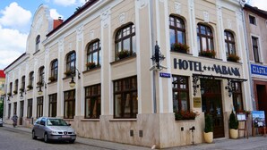 Un hotel con fachada clásica, amplias ventanas con jardineras y un cartel que indica que es hotel y banco.