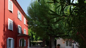 A courtyard with a red building, a tree, and a small seating area.