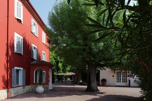 Un patio con un edificio rojo, un árbol y un pequeño rincón con asientos.