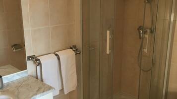 A bathroom with a glass-enclosed shower, a sink with a marble countertop, and a toilet.