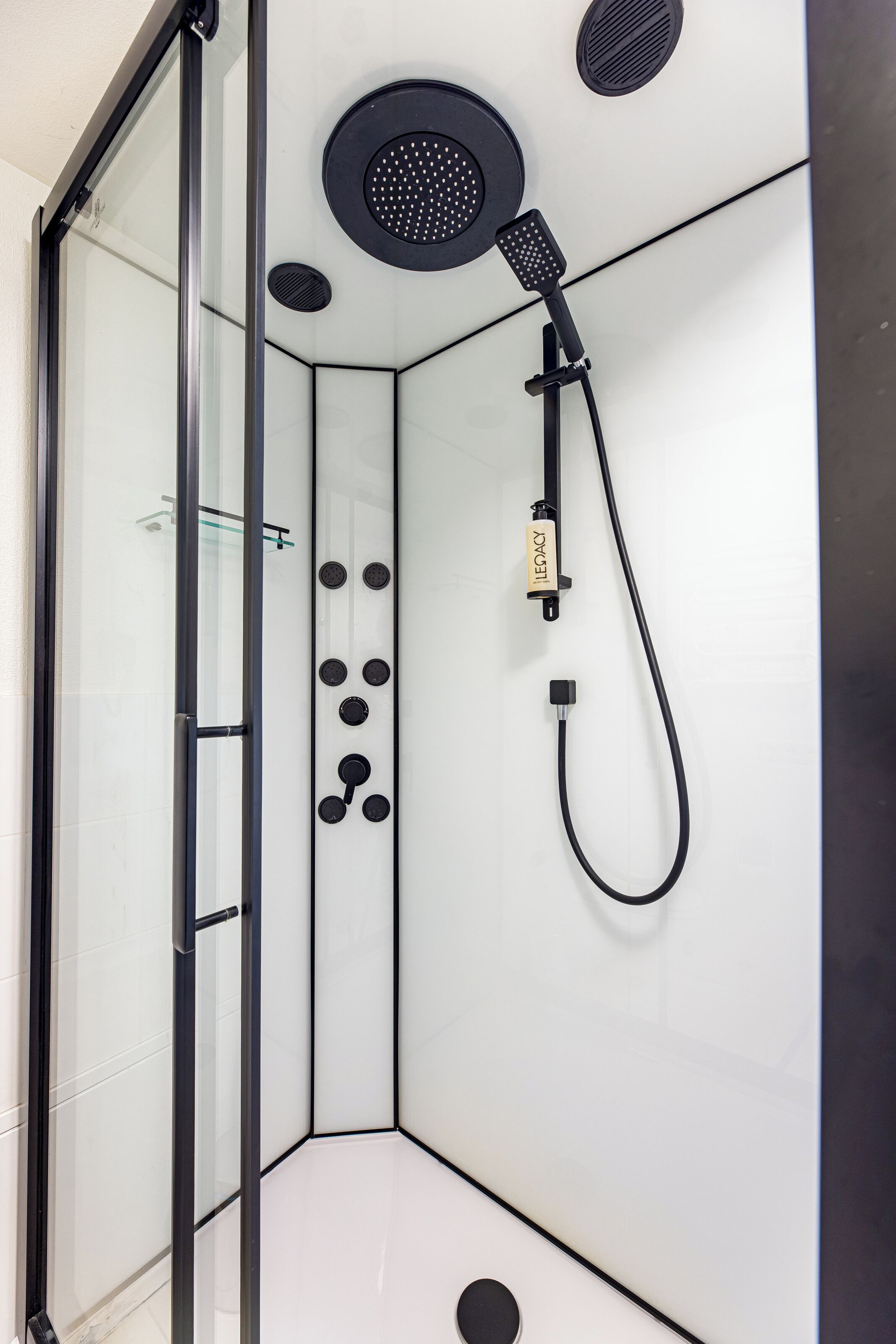 A modern shower with a handheld showerhead and a handheld massager.