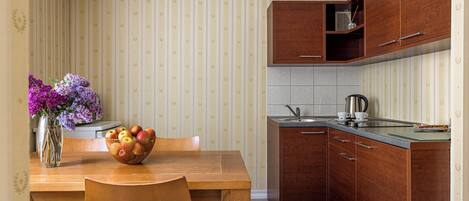 Une cuisine de taille réduite avec des meubles de rangement en bois, une table à manger avec des chaises et un vase rempli de fleurs.