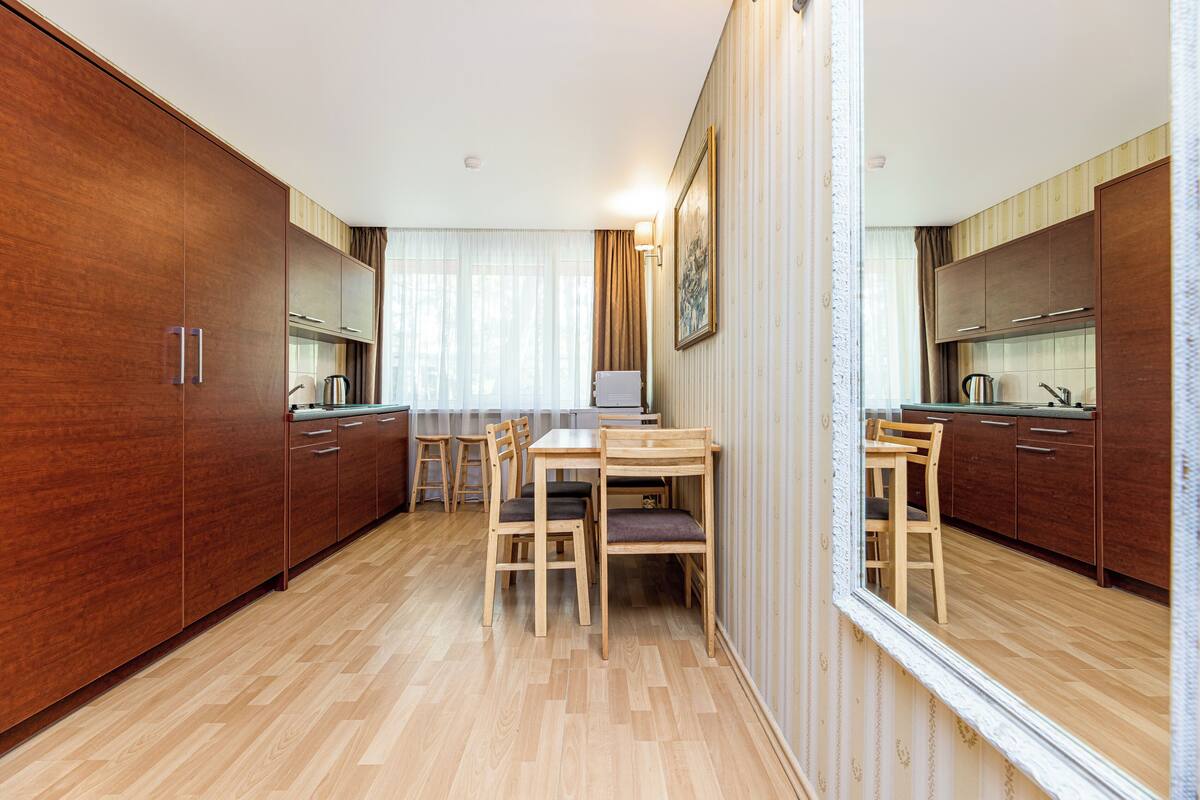 A modern kitchen with wooden cabinets, a dining table, and chairs.